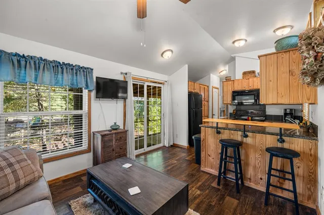 a living room with stainless steel appliances furniture a rug and a view of kitchen
