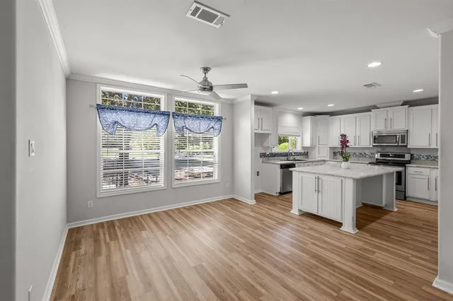 a kitchen with granite countertop a stove top oven a sink and white cabinets