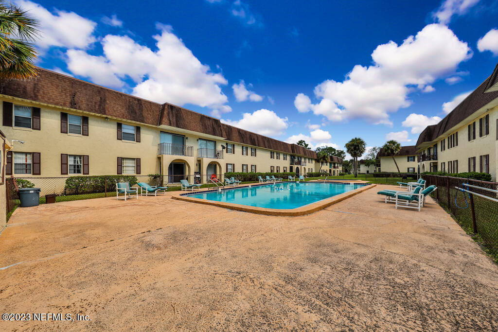 1735 El Camino Road, Unit 5 Jacksonville, FL 32216 - Photo 14 of 32 a view of a white house with a swimming pool and a yard