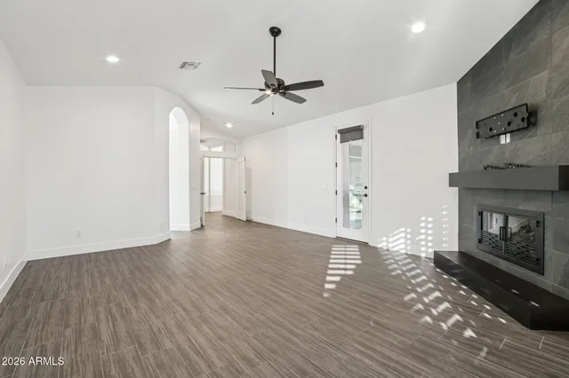 a view of an empty room with wooden floor fireplace and a window