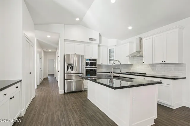 a kitchen with stainless steel appliances granite countertop a sink a stove and a wooden floors