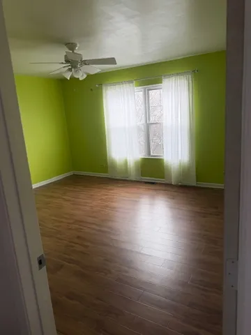 a view of an empty room with window and wooden floor