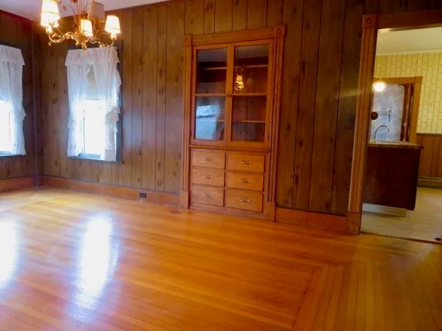 a view of a hallway with wooden floor and cabinet