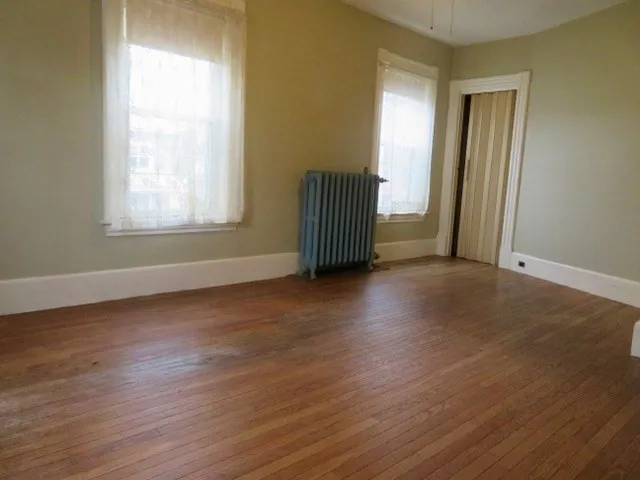 an empty room with wooden floor and windows