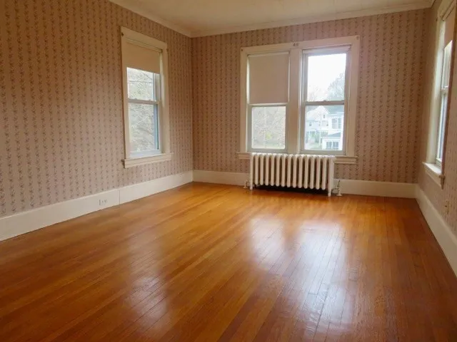 an empty room with wooden floor and windows