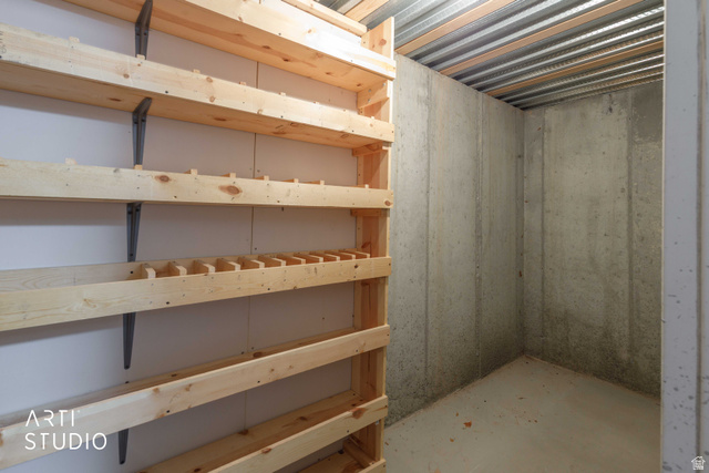 2327 Bluff Ridge Drive Syracuse, UT 84075 - Photo 40 of 66 Storage area featuring built-in wooden shelving, a corrugated metal ceiling, and concrete walls