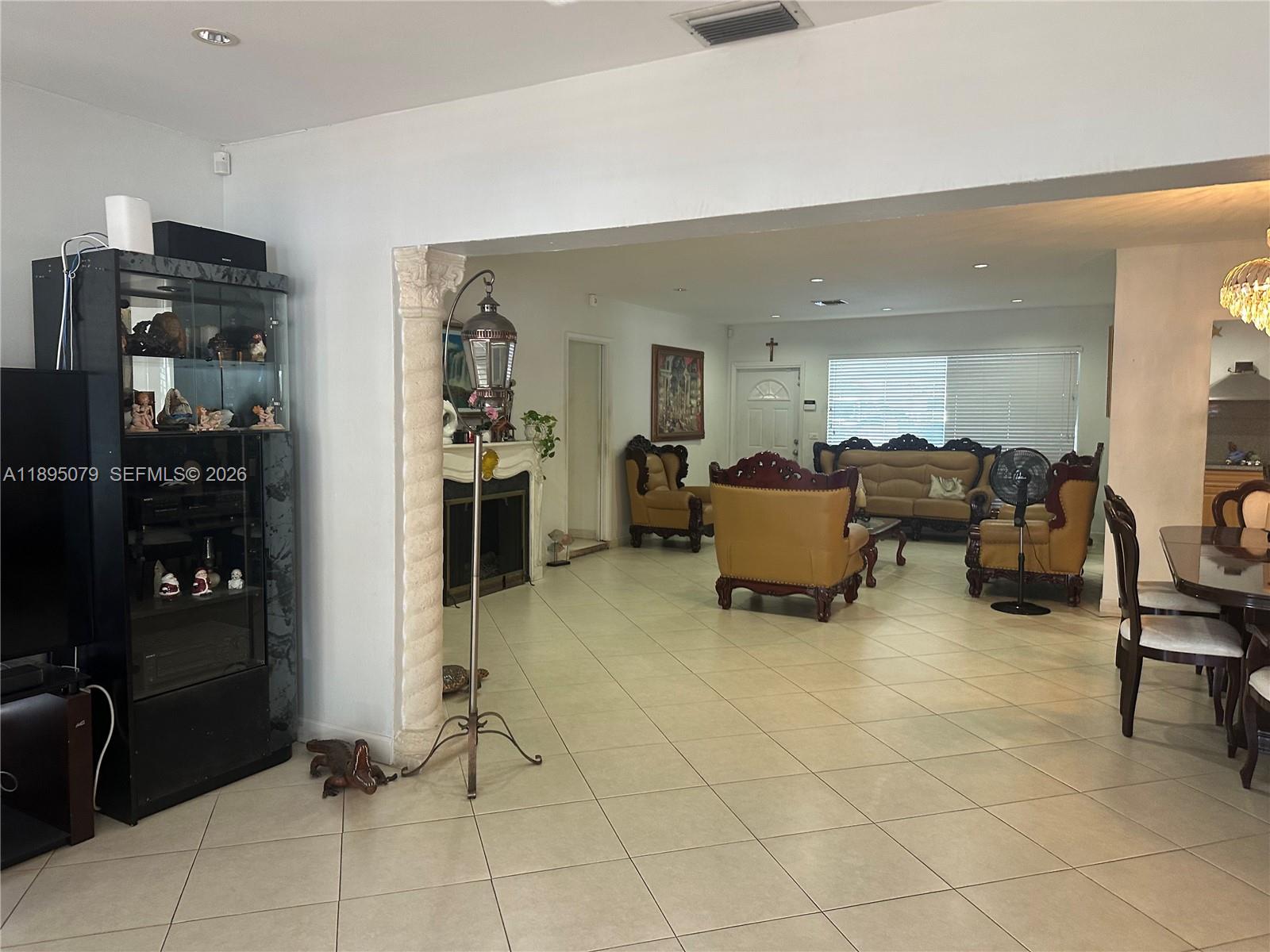 12941 Auralia Road North Miami, FL 33181 - Photo 2 of 32 a living room with furniture a table and a refrigerator