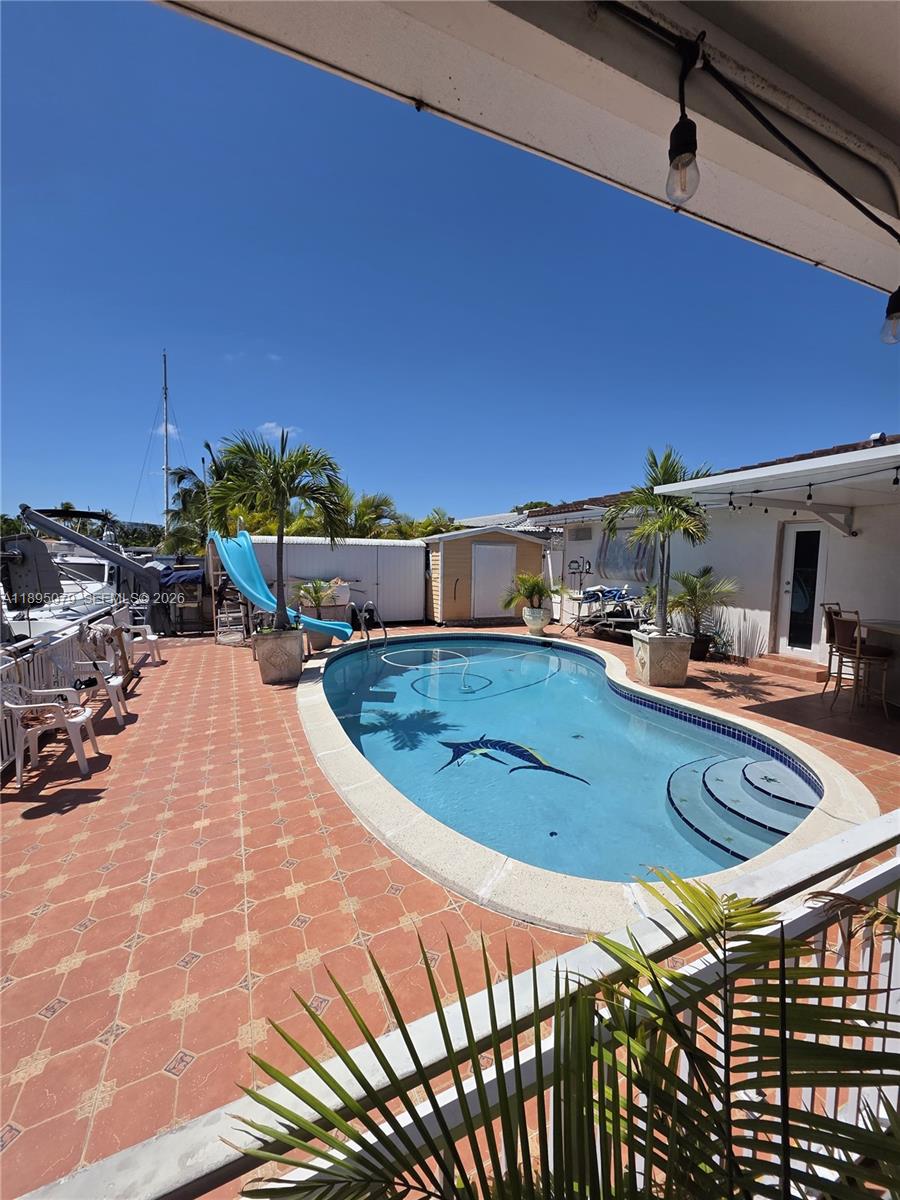 12941 Auralia Road North Miami, FL 33181 - Photo 24 of 32 a view of a swimming pool with a lounge chairs