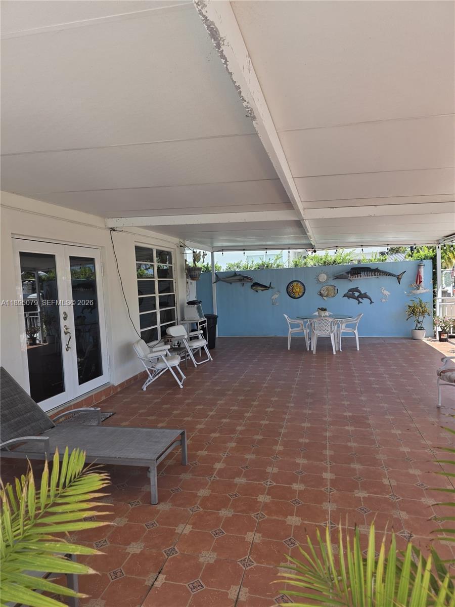 12941 Auralia Road North Miami, FL 33181 - Photo 9 of 32 a view of a patio with table and chairs under an umbrella with a barbeque