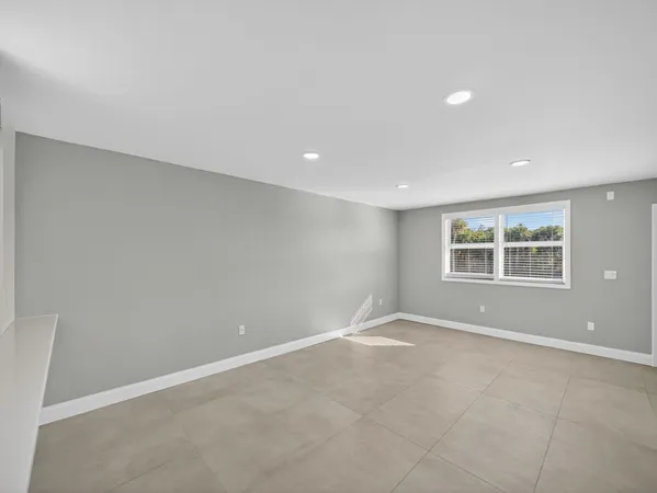 an empty room with a ceiling fan and window