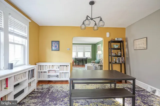 a living room with a dining table and a bookshelf with wooden floor