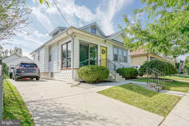 a view of a white house with a small yard and large tree
