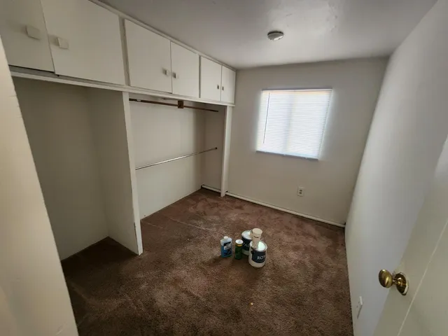 a view of an empty room with windows & cabinet