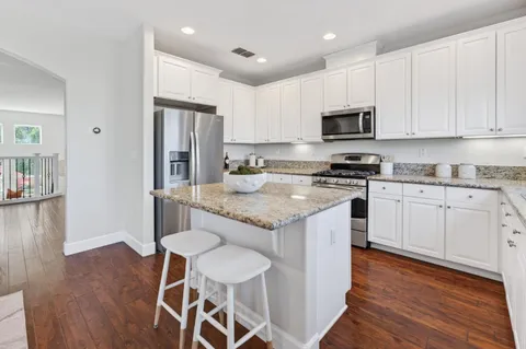 a kitchen with granite countertop white cabinets and stainless steel appliances