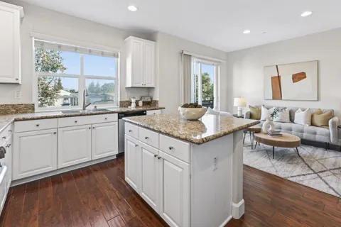 a kitchen with a sink dishwasher a stove a dining table and chairs with wooden floor