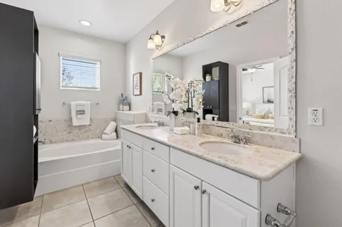 a bathroom with a granite countertop sink mirror bathtub and toilet