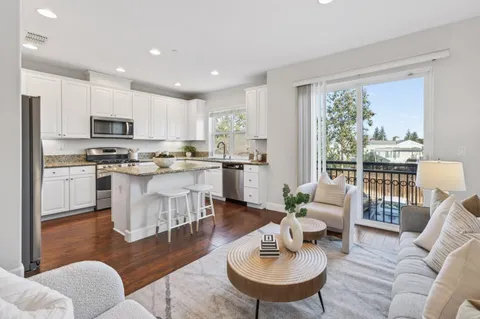 a living room with stainless steel appliances furniture and a kitchen view