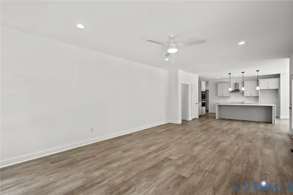 an empty room with wooden floor and kitchen view