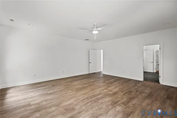 an empty room with wooden floor and ceiling fan