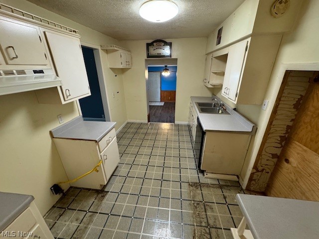 Kitchen with light tile patterned flooring, sink, a textured ceiling, and white cabinets