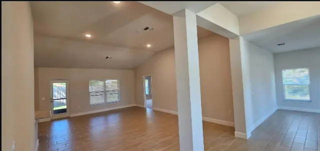 a view of empty room with window and wooden floor