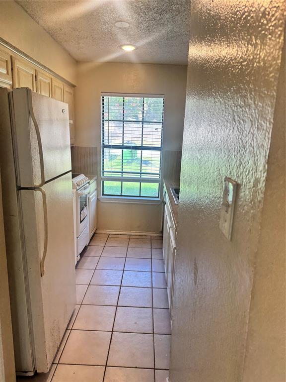 5617 Mansfield Road Arlington, TX 76017 - Photo 10 of 15 Galley kitchen featuring tiled flooring, a window with horizontal blinds, built-in cabinetry, and recessed lighting