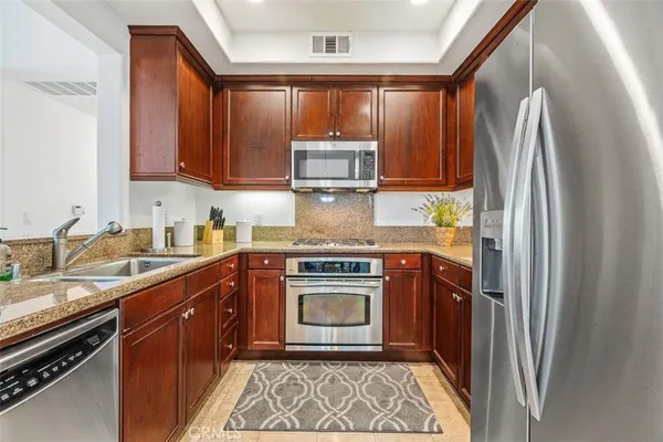 a kitchen with stainless steel appliances granite countertop a refrigerator stove and sink