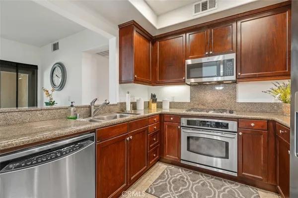 a kitchen with stainless steel appliances granite countertop a stove a sink and a microwave