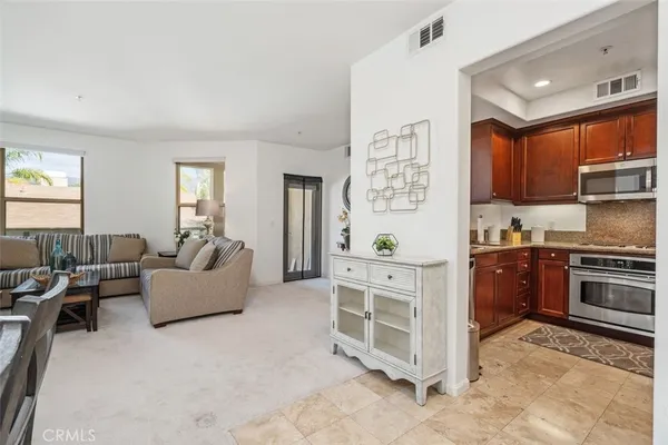 a large living room with stainless steel appliances granite countertop a couch and a window