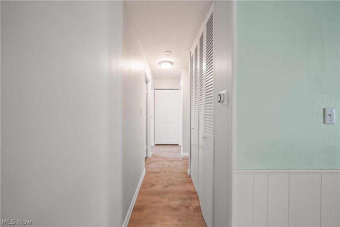 3796 North Santom Road Stow, OH 44224 - Photo 13 of 30 Hallway featuring wood-finish flooring, white walls, and a light-colored accent wall with beadboard wainscoting