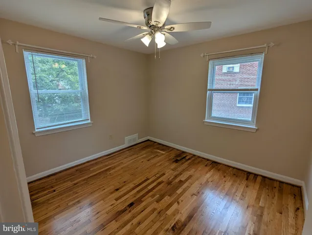 a view of an empty room with window and wooden floor
