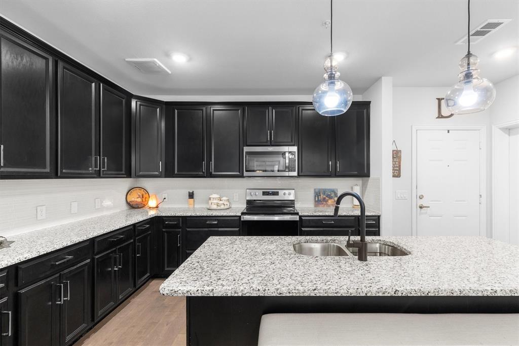 651 Watters Road, Unit 5205 Allen, TX 75013 - Photo 5 of 31 a kitchen with kitchen island granite countertop stainless steel appliances sink stove microwave and cabinets