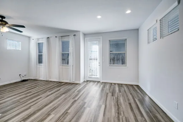 a view of an empty room with wooden floor and a window