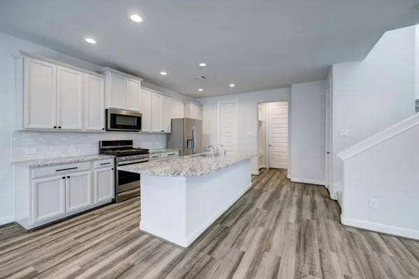 a large kitchen with a center island wooden floor stainless steel appliances and cabinets