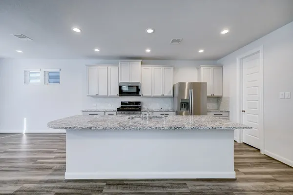 a large kitchen with stainless steel appliances granite countertop a stove a sink a refrigerator and a granite counter tops