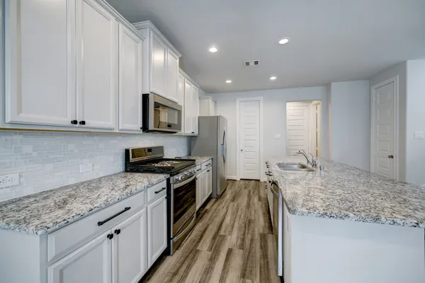 a kitchen with granite countertop stainless steel appliances sink stove microwave and cabinets