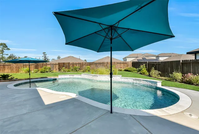a view of pool with table and chairs under an umbrella