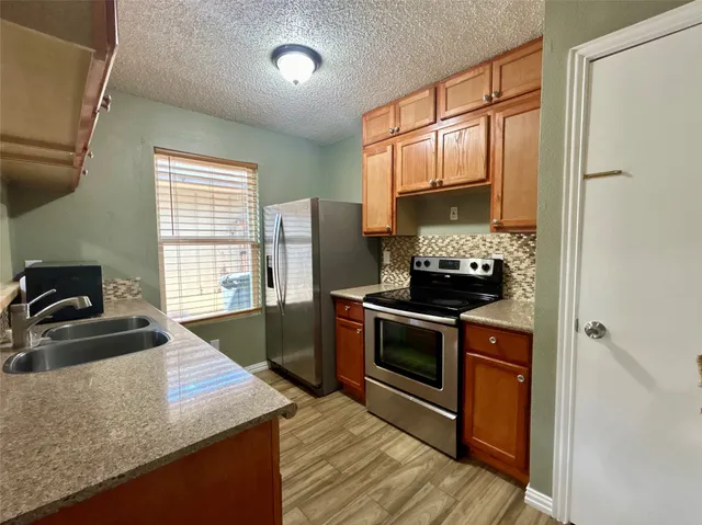 a kitchen with granite countertop a sink stove and refrigerator