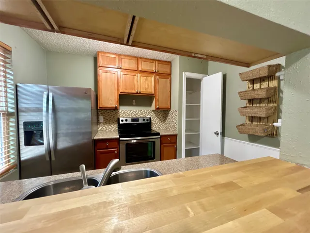 a kitchen with stainless steel appliances kitchen island granite countertop a refrigerator and a sink