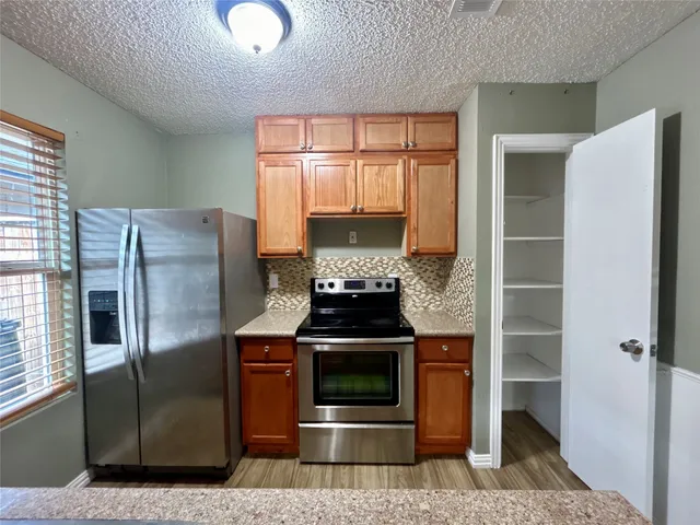 a kitchen with stainless steel appliances granite countertop a refrigerator and a stove