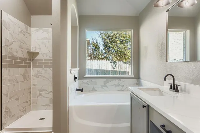 a bathroom with a tub a sink and mirror