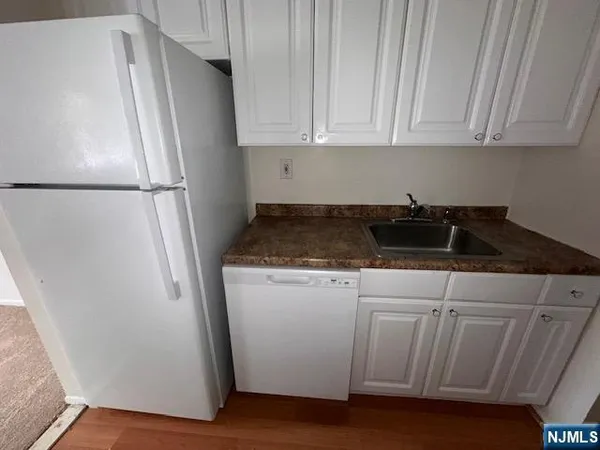 a kitchen with granite countertop white cabinets and refrigerator