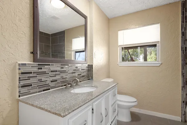 a bathroom with a granite countertop sink and a toilet