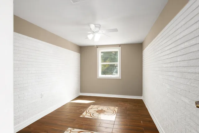 a view of an empty room with window and wooden floor