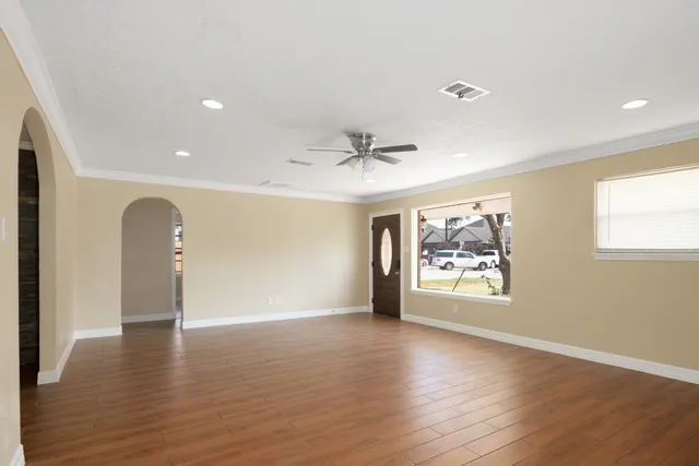 a view of an empty room with a window and wooden floor
