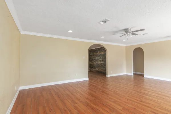 an empty room with wooden floor and a ceiling fan