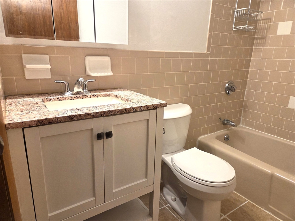 586 Boston Post Road East, Unit 6 Marlborough, MA 01752 - Photo 11 of 17 a bathroom with a granite countertop toilet a sink and bathtub