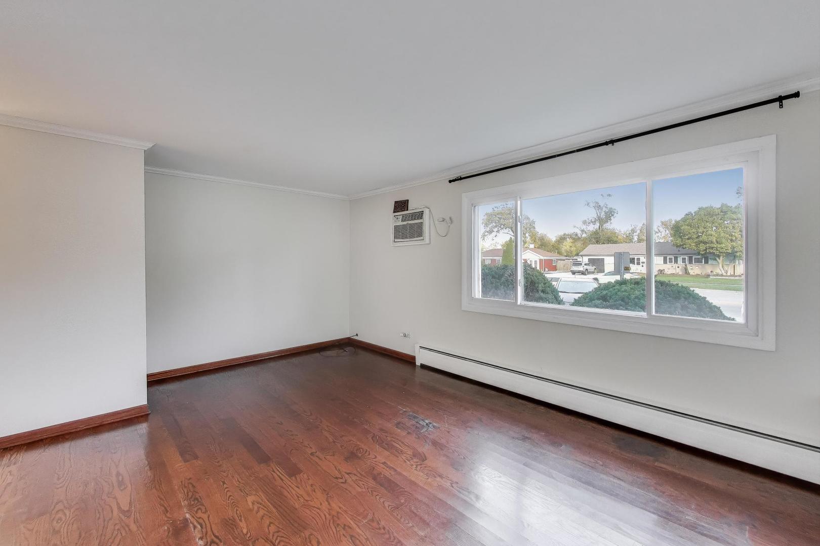 9454 Potter Road Des Plaines, IL 60016 - Photo 5 of 33 a view of an empty room with wooden floor and a window