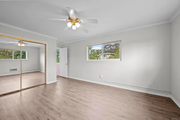 a view of an empty room with a window and wooden floor