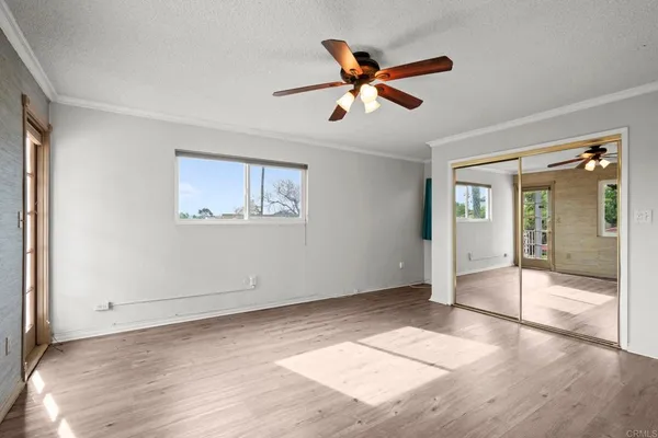 a view of empty room with wooden floor and fan